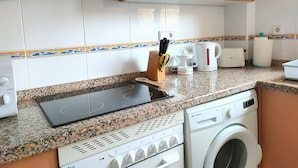 A kitchen with a built-in stove, a microwave, a toaster, and a washing machine. - Holiday Apartment - Javea Puerto - 2bedr 2 Bath (Javea)