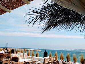 Eine Terrasse am Meer mit Korbmöbeln und Blick auf den Ozean.