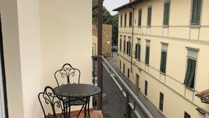 A balcony with a metal table and chairs, a tiled floor, and a view of neighboring buildings. - CasaGiorgio a stone's throw from the historic center (Firenze)