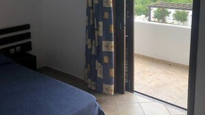 Een slaapkamer met een bed, een gordijn en een schuifdeur naar een balkon.