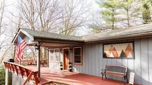 A wooden deck with a bench, an American flag, and a sign indicating 'Fall'.