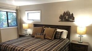 A bedroom with a bed, two bedside tables, a window, and a wall decoration.