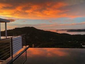 Un bâtiment moderne doté d’un balcon offrant une vue panoramique sur un paysage magnifique au coucher du soleil.