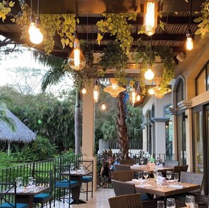 Enjoy dining under a thatched-roof structure amidst lush greenery.