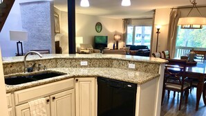 Uma cozinha com bancadas de granito, máquina de lavar louça e área de jantar com mesa e cadeiras.