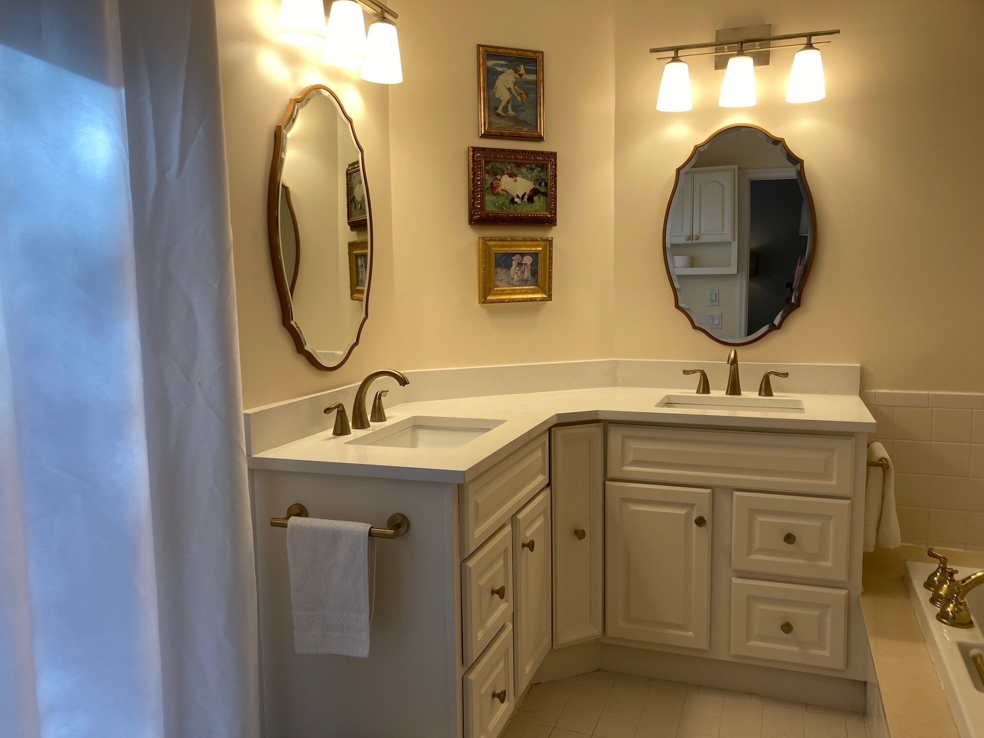 Une salle de bain avec un meuble-lavabo blanc, deux vasques, un grand miroir et des appliques murales.