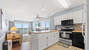 A modern kitchen with white cabinets, a microwave, an oven, and a dining area with a table and chairs.