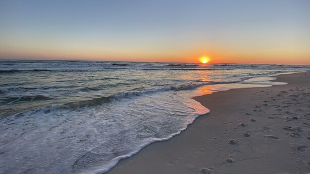 Una playa con olas y un atardecer.
