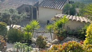Un bâtiment de style méditerranéen, avec des toits couverts de tuiles en terre cuite, entouré d’une végétation luxuriante et offrant une vue sur un paysage côtier.