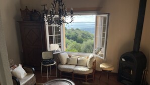 Un salon chaleureux avec un canapé, une table, une cheminée et une vue sur l’extérieur.