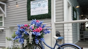 A bicycle with a floral arrangement in front of a building with a sign that reads "BEACHY BEAN Coffee Co." - Golf Cart - 2 min to Beach - Pool - Walk to Shops & Dining! (Santa Rosa Beach)