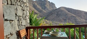 Un balcon avec une table dressée pour deux personnes, offrant une vue sur un paysage montagneux.