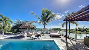 A poolside area with lounge chairs, a thatched umbrella, and a view of the ocean. - Villa Zen – Sea View Villa with Pool & Jacuzzi (Cul-de-Sac)