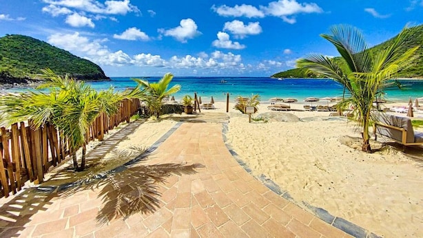 A beach pathway leading to a sandy beach with palm trees and lounge chairs. - Villa Zen – Sea View Villa with Pool & Jacuzzi (Cul-de-Sac)