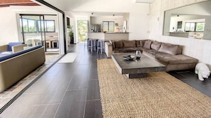 A modern living room with a sectional sofa, a coffee table, and a large mirror. - Villa Zen – Sea View Villa with Pool & Jacuzzi (Cul-de-Sac)