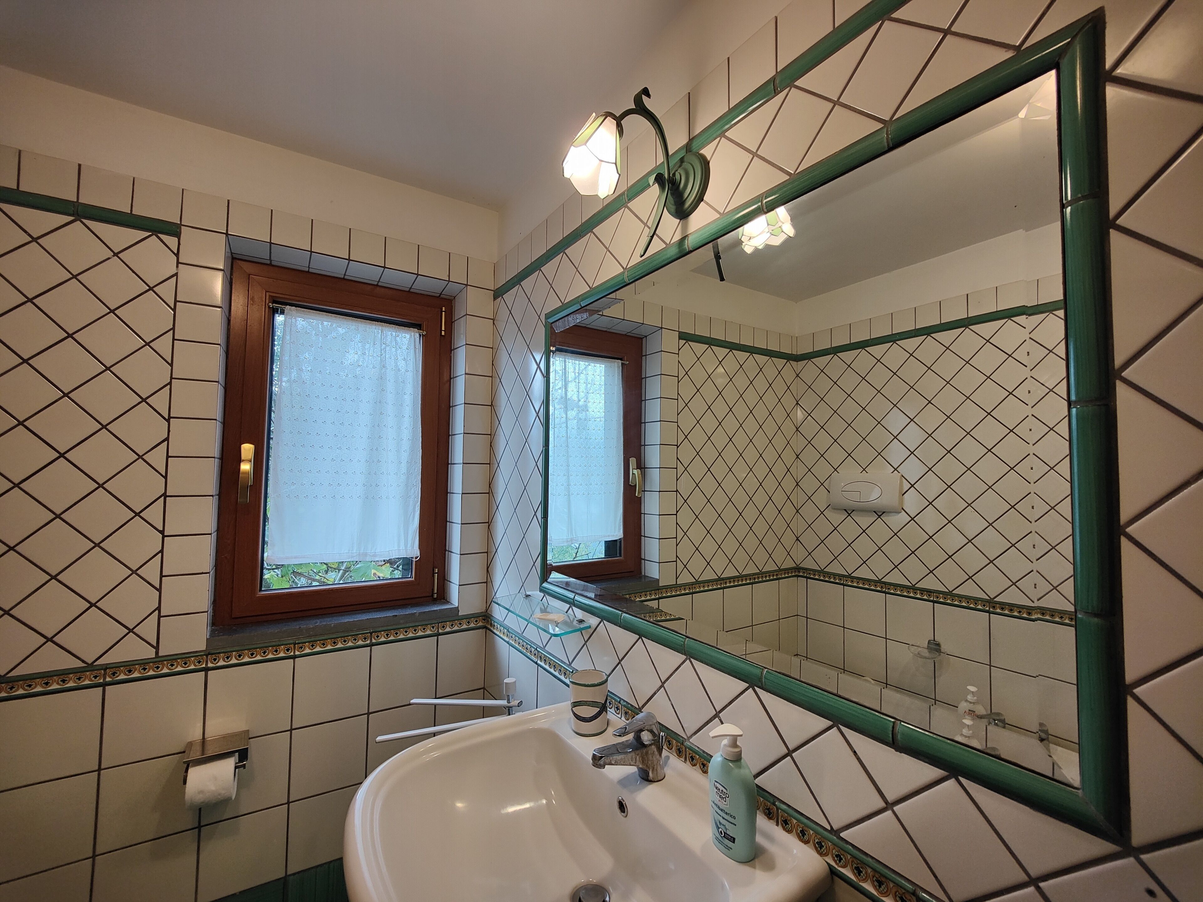 Een badkamer met een wastafel, spiegel en twee ramen.