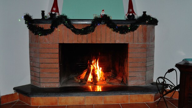 A fireplace with a brick surround, adorned with Christmas decorations and a garland.