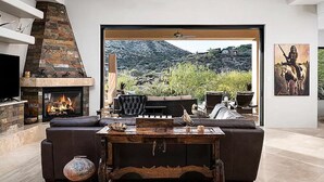 A modern living room with a fireplace, leather sofa, and a view of a mountainous landscape. - 5 Star INFINITY POOL Saguaro Mountain Desert House (Scottsdale)