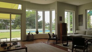 Amplia sala de estar con ventanas grandes, un sofá, una mesa de centro y una chimenea.