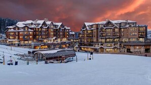 Una località turistica innevata con diversi edifici caratterizzati da architettura tradizionale e finestre illuminate.