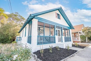 Ein eingeschossiges Haus mit Satteldach, einer Laube mit blauen Geländern und einem gepflegten Garten.
