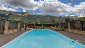 Piscina con montañas al fondo, rodeada por una cerca y un cartel que indica que no se permite bucear.