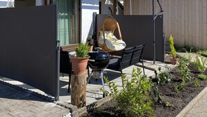 Une terrasse avec un barbecue, du mobilier d’extérieur et des plantes en pot.