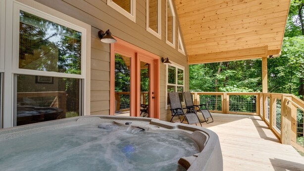 Un jacuzzi en una terraza de madera con vistas a un bosque.