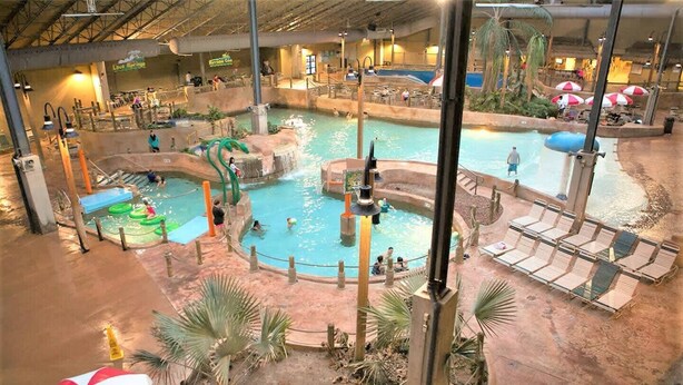 An indoor water park with multiple pools, slides, and a seating area with umbrellas. - Beach, lake & pool within walking distance! Outdoor fire pit area, Game room (Albrightsville)