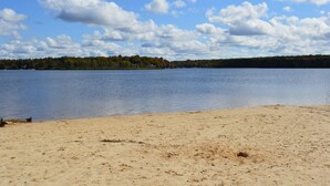 A beach with a sandy shore and a calm lake. - Beach, lake & pool within walking distance! Outdoor fire pit area, Game room (Albrightsville)