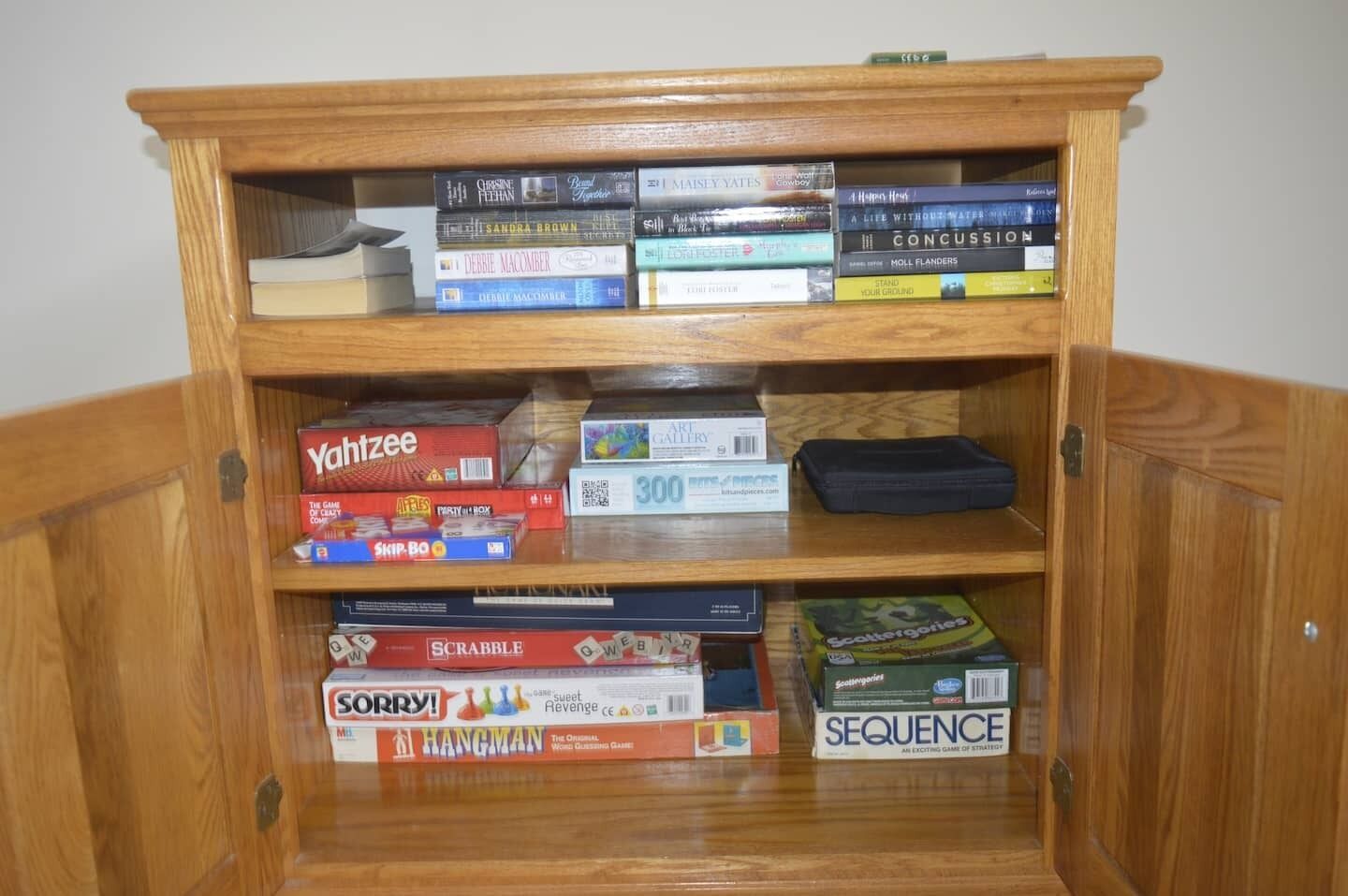 A wooden bookshelf with various board games and a card game box.