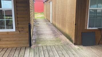 A wooden deck leading to a building with a red exterior and a satellite dish.
