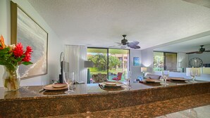 A modern kitchen with granite countertops, a dining area with a view, and a ceiling fan. - Affordable quality in central location, Oceanside Complex  (Kihei)