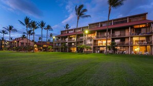 A multi-story hotel with balconies, a lawn in the foreground, and palm trees. - Affordable quality in central location, Oceanside Complex  (Kihei)