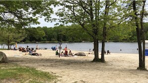 A beach with people relaxing and sunbathing, a lake in the background, and trees providing shade. - Serendipity, Sauna,Swimming Pool & Hot Tube, billiard, Secluded (Albrightsville)