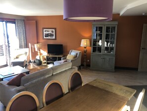 Un salon comprenant un canapé, un téléviseur, un meuble et une table à manger.