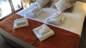 A neatly made bed with white linens, multiple pillows, and folded towels on a brown bed runner. - Gorgeous appartment in Avoriaz (Avoriaz)