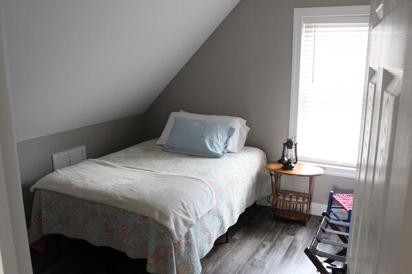 Une chambre à coucher avec un lit, une petite table sur laquelle est posée une lanterne, et une chaise.
