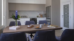 Eine moderne Küche mit weißen Schränken, einer Marmorarbeitsplatte und einem Essbereich mit einem Holztisch und Stühlen.