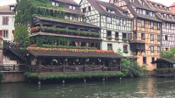 Un bâtiment situé au bord de la rivière, doté d’une structure à plusieurs étages, de balcons en bois et de jardinières.