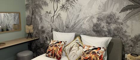 A bedroom with a large bed, two pillows with bird prints, a bedside table, a lamp, and a wall mural of bamboo and birds.