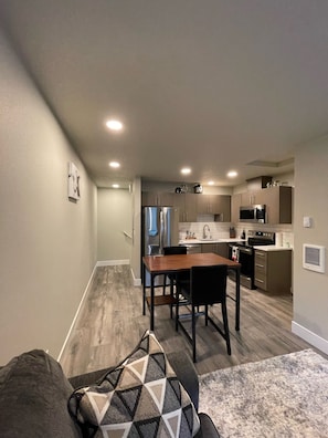 Cozy living space with a dining area and kitchen, featuring a sofa, dining table, and modern appliances.