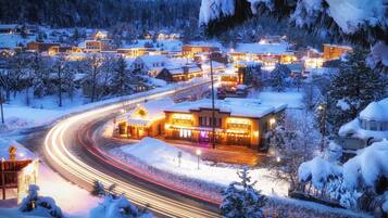 Une ville recouverte de neige, avec des bâtiments illuminés et une route sinueuse.