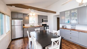 A modern kitchen with grey cabinets, a black dining table, white chairs, and wooden floors. - Lexington Beach house, On the water with private beach (Lexington)