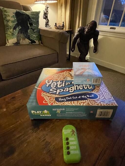 A box of 'Yeti in Spaghetti' game on a wooden table with a remote control beside it.
