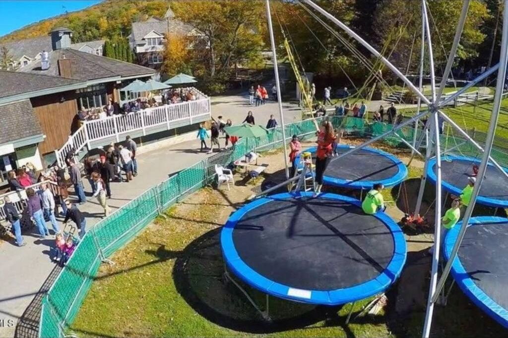 A trampoline park with multiple trampolines and a crowd of people.
