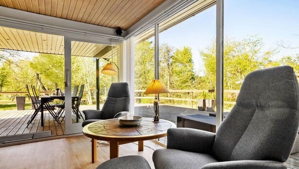 Eine Terrasse im Freien mit einem runden Tisch, zwei grauen Sesseln und einer Lampe.