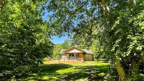 Eine Lodge mit einer überdachten Terrasse, umgeben von üppiger Vegetation und Bäumen.
