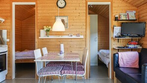 Un accogliente interno di una baita con zona pranzo, televisore e libreria.