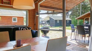Un accogliente interno di una baita con zona pranzo, ampie finestre e vista sui dintorni.